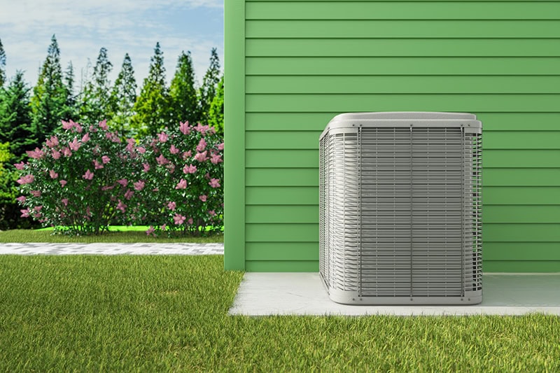 AC unit installed outside of a green home in the spring time.