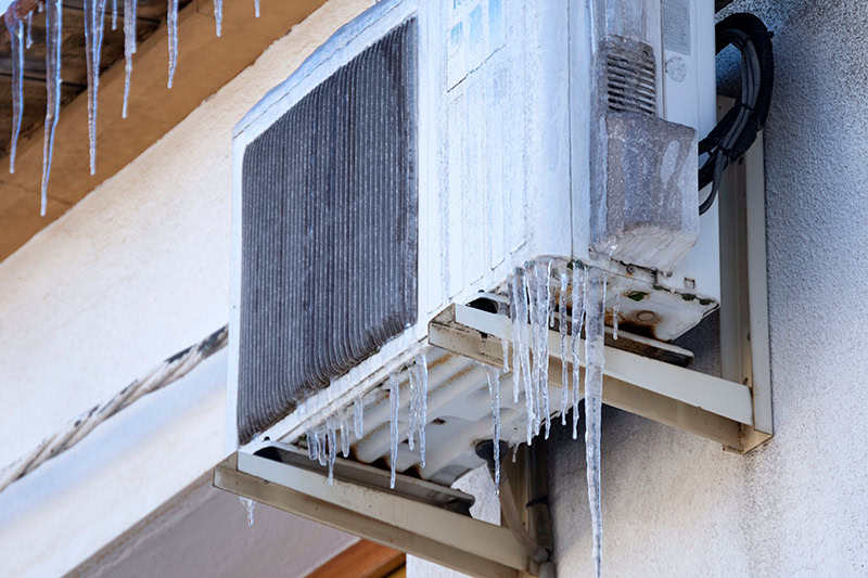 Photo of a heat pump installed outside with icicles.